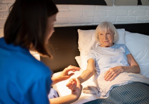 Pulse check. Doctor checking pulse of an elderly patient and looking focused